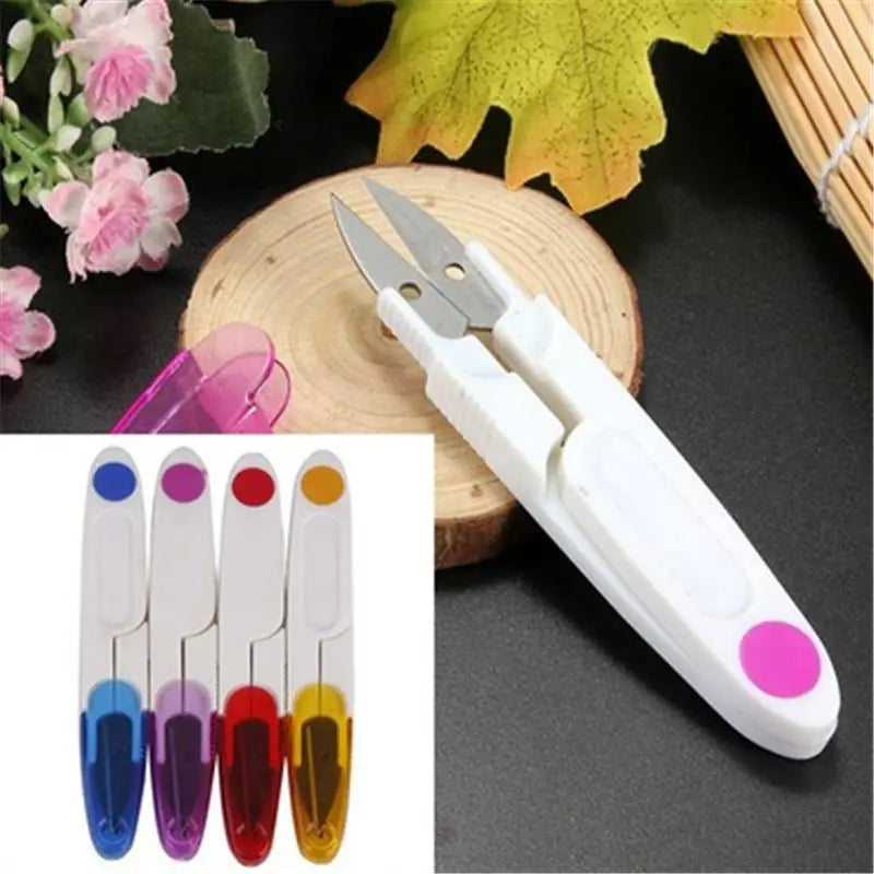 A pair of white-handled thread snips with stainless steel blades, displayed alongside colorful caps shown in blue, red, purple, and orange, indicating available color options for the product.