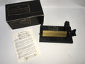 The image shows 'The Little Amanda Smocking Pleater' with its original box, instruction manual, and 12 needles. The pleater itself is black and gold in color.