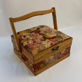 Small wooden sewing box with floral fabric top on a white background